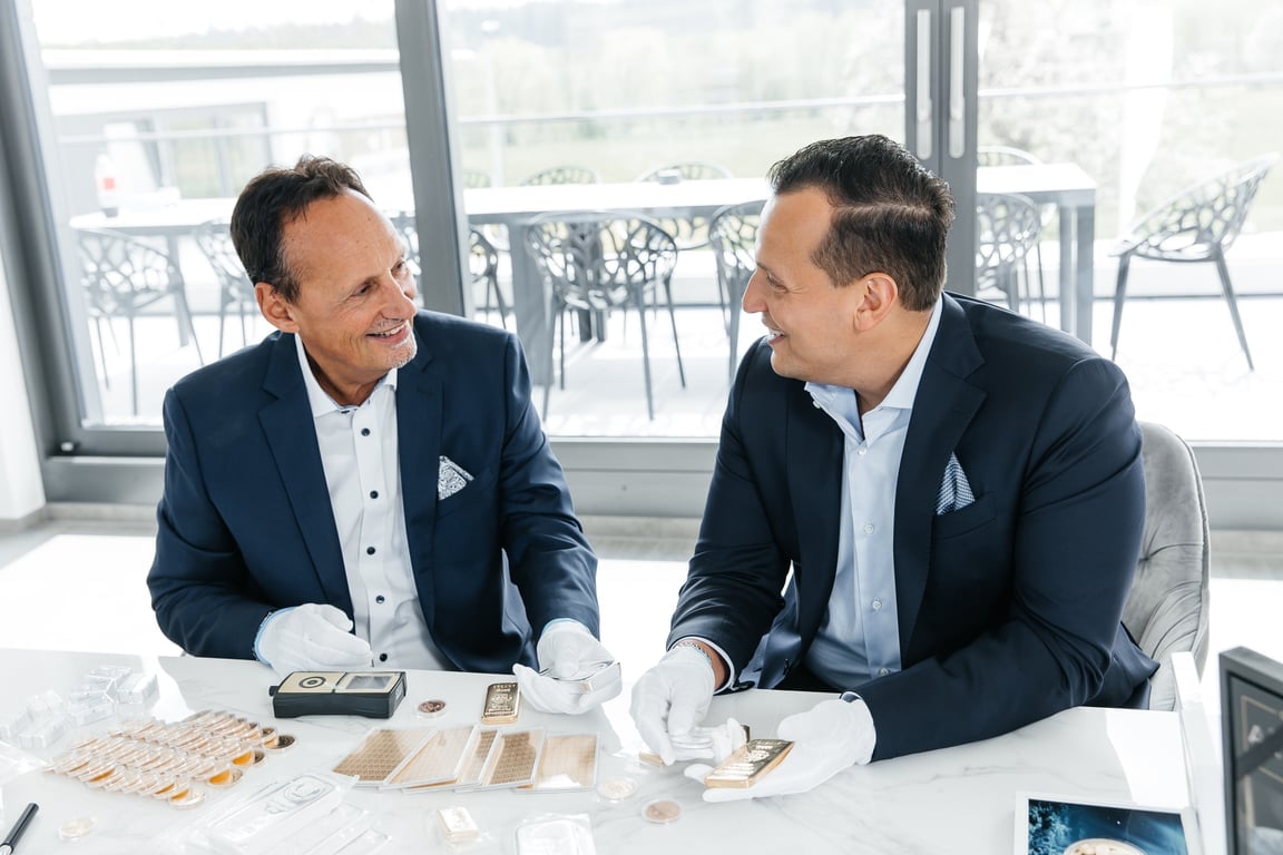 Jürgen A. Kettner and Dominik Kettner with gold bars and coins in the office