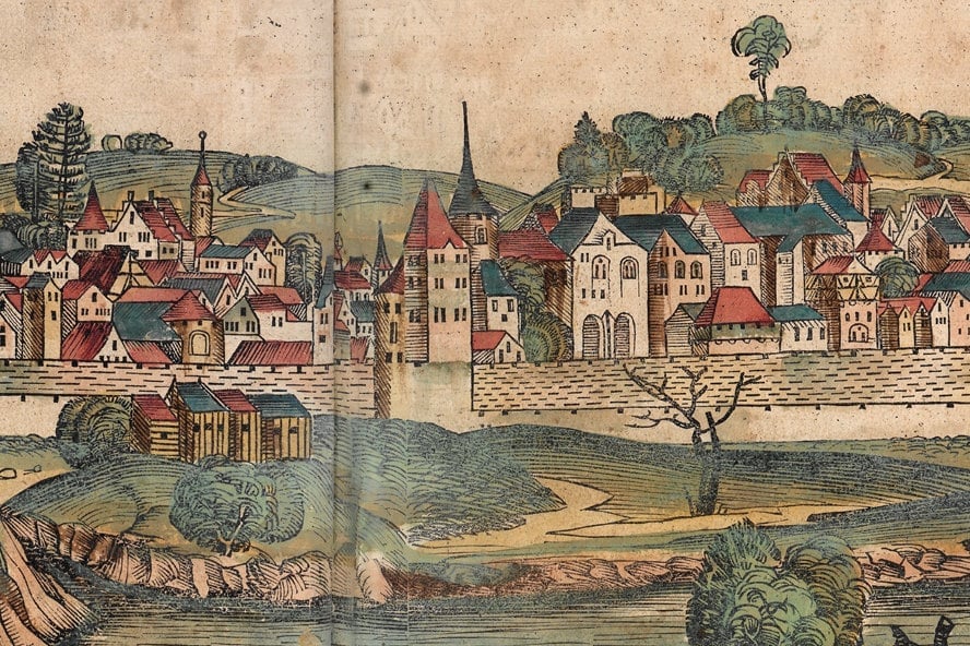 Coloured woodcut: closely packed houses with red and blue roofs behind a city wall, in front of it huts, meadows and water