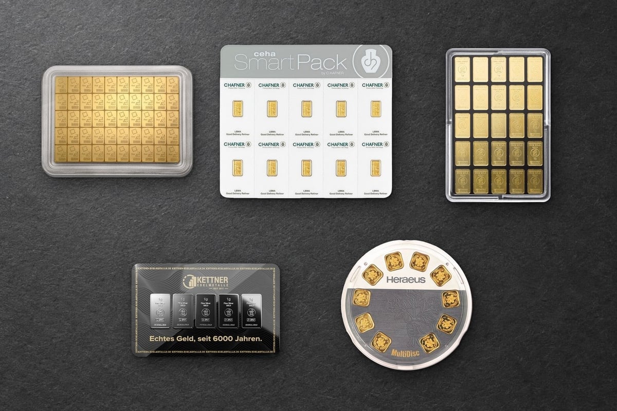 Fünf Packungen kleiner Barren von oben auf dunkelgrauem Papier: eine goldene Tafel in einer Kapsel, ein weißes Kartenset mit zehn Goldbarren, eine Box mit fünfundzwanzig Goldbarren, eine schwarze Karte mit fünf Silberbarren und eine runde Verpackung mit zehn Goldbarren
