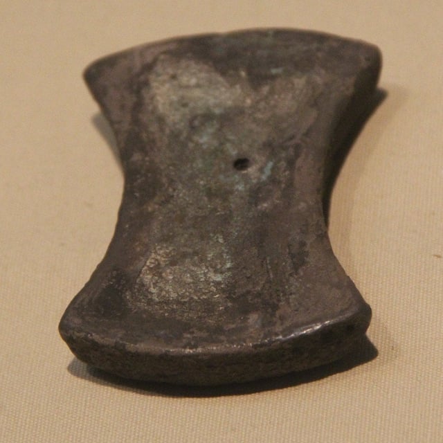 Flacher, in der Mitte eingezogener Silberbarren, dunkel angelaufen, auf hellem Grund