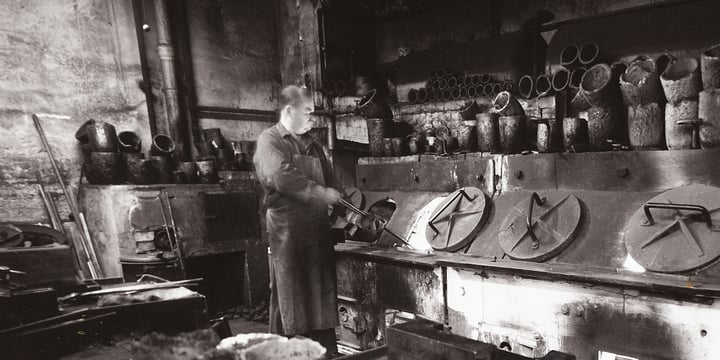 Schwarz-Weiß-Aufnahme: ein Arbeiter vor alten Schmelzöfen