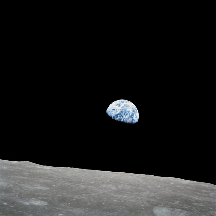 The half‑lit Earth above the grey lunar horizon against a black sky
