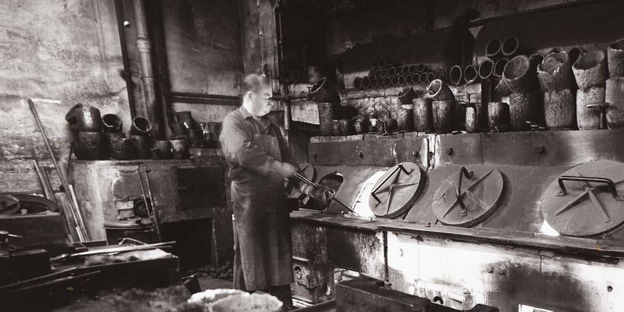 Schwarz-Weiß-Aufnahme: ein Arbeiter vor alten Schmelzöfen