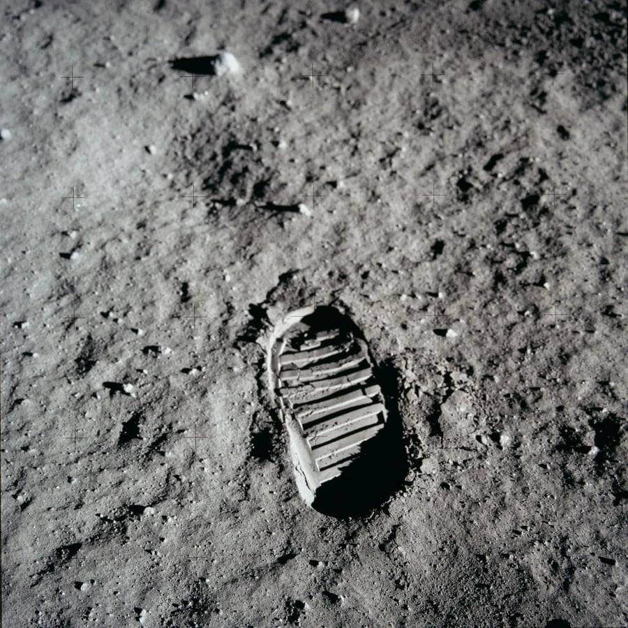 A boot print with cross ridges in grey lunar dust, photographed at an angle from above